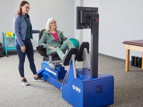 Elderly patient performing exercise on Eccentron while clinician monitors
