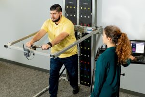 Injured worker performs a push test on Prism functional evaluation device while Clinician monitors objective data readout