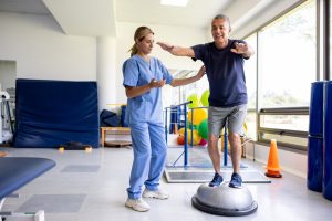 Patient performs balance training exercise with physical therapist