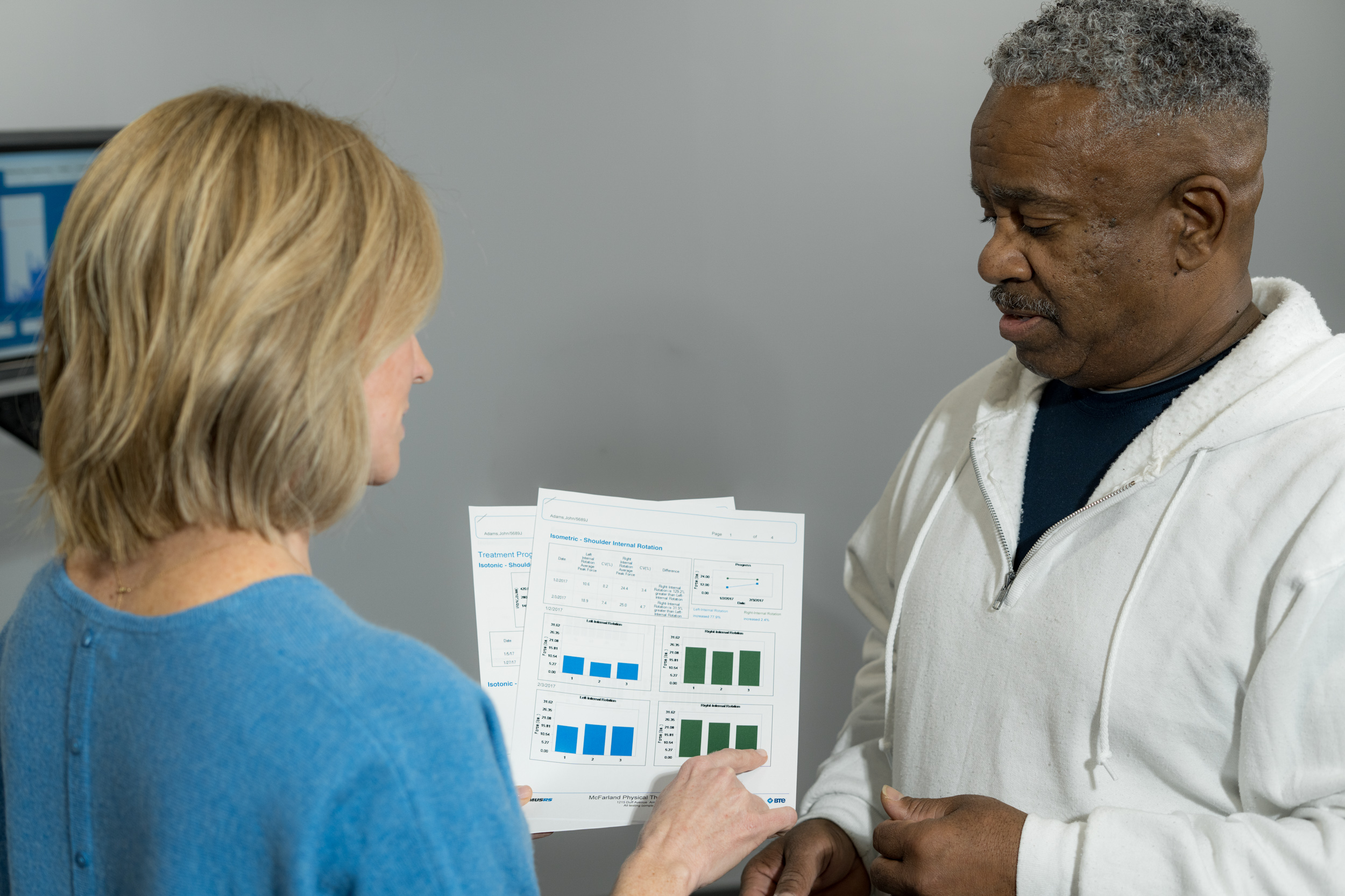 Physical therapist reviews objective progress report with patient